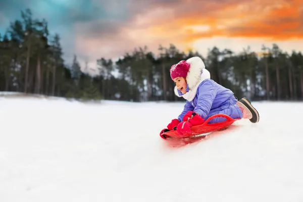 Dívka sklouzla na saně talíř sníh v zimě — Stock fotografie