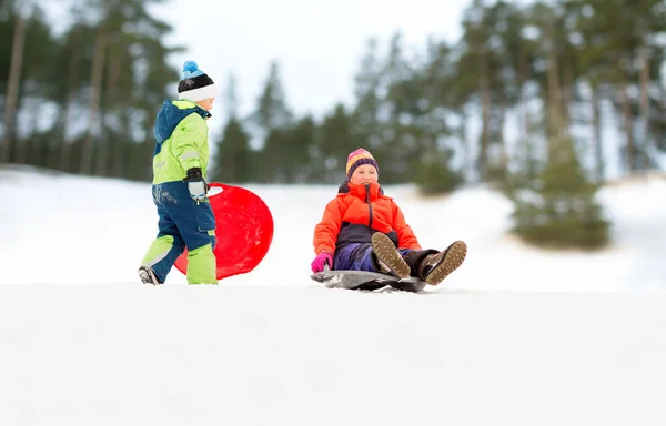 Boldog gyerekek csúszik szánkón le a hegyről télen — Stock Fotó