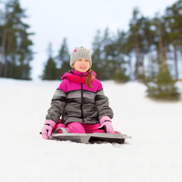 Szczęśliwa dziewczynka na sankach nad zaśnieżonym zimowym parkiem — Zdjęcie stockowe