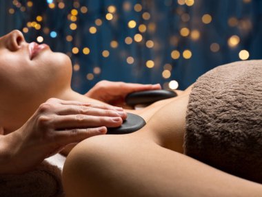 close up of woman having hot stone massage at spa clipart