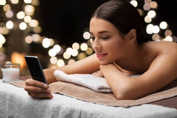 Kvinna med smartphone på spa eller massage salong — Stockfoto