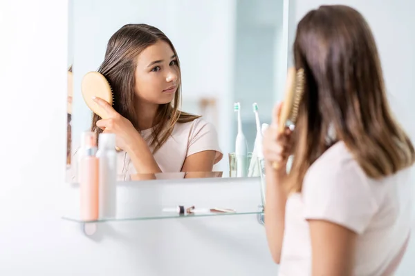 Teenager-Mädchen bürstet Haare mit Kamm im Badezimmer — Stockfoto