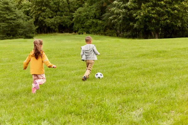 Niños pequeños con pelota jugando fútbol en el parque —  Fotos de Stock