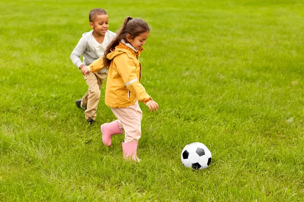 Crianças pequenas com bola jogando futebol no parque — Fotografia de Stock