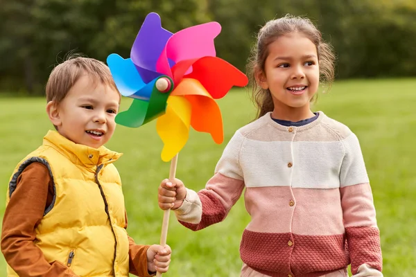 Crianças felizes com pinwheel se divertindo no parque — Fotografia de Stock