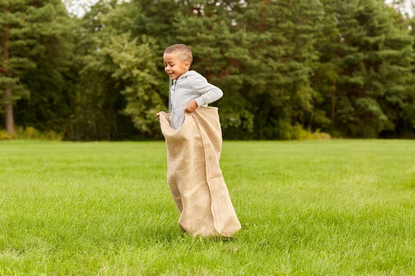 Heureux garçon jouer jeu de saut de sac au parc — Photo