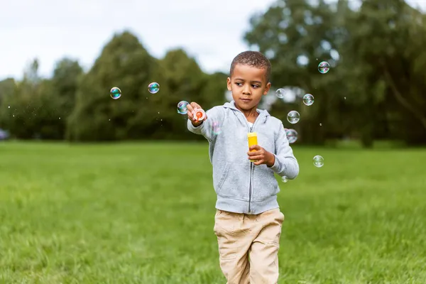 Μικρό αγόρι παίζει με σαπουνόφουσκες στο πάρκο — Φωτογραφία Αρχείου