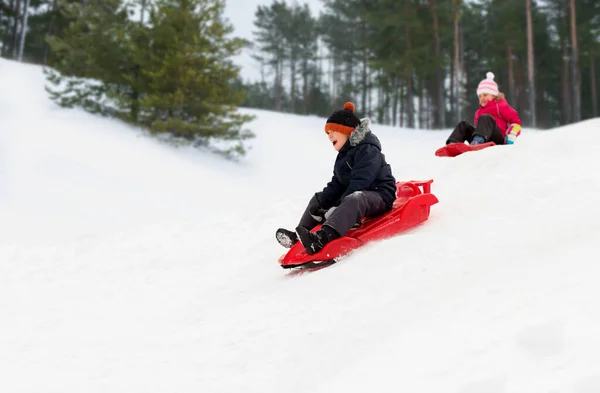 Boldog gyerekek csúszik szánkón le a hegyről télen — Stock Fotó