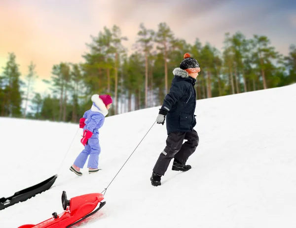 Barn med slädar klättra snö kulle på vintern — Stockfoto
