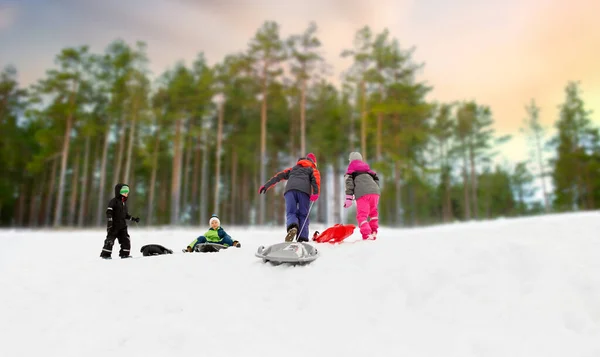 Barn med slädar klättra snö kulle på vintern — Stockfoto