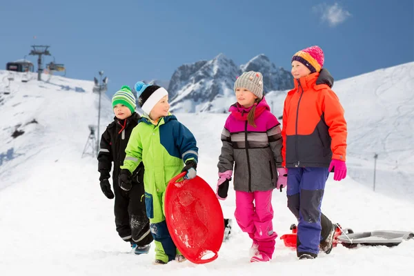 Heureux petits enfants avec des traîneaux en hiver — Photo