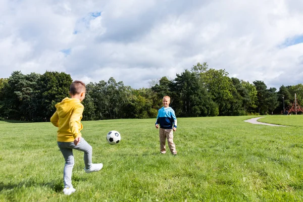 Meninos felizes com bola jogando futebol no parque — Fotografia de Stock