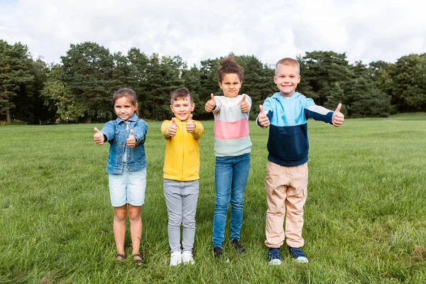 Glückliche Kinder zeigen Daumen hoch im Park — Stockfoto