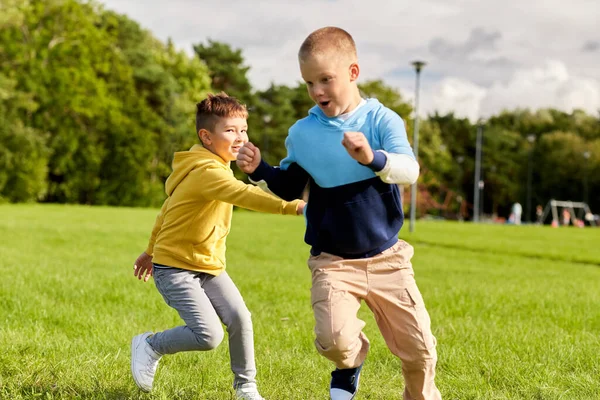 Twee gelukkige jongens spelen tag game in park — Stockfoto