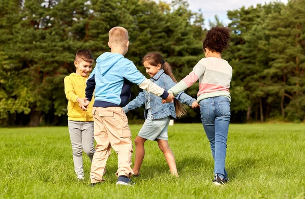 Glada barn leker rund dans i parken — Stockfoto