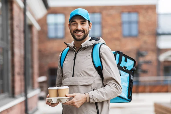 Glücklicher Lieferant mit Thermobeutel und Kaffee — Stockfoto