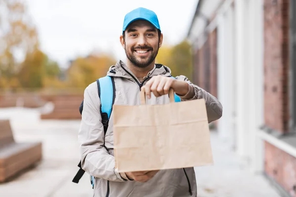 Livreur heureux avec nourriture à emporter dans un sac en papier — Photo