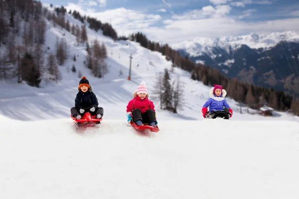 冬天, 孩子们在雪丘下滑雪橇 — 图库照片