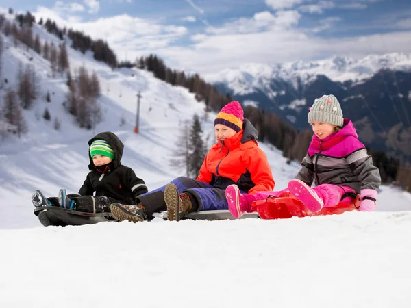 Glückliche kleine Kinder, die im Winter auf Schlitten rutschen — Stockfoto