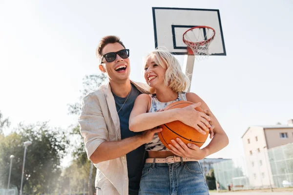 Счастливая пара играет в баскетбол на детской площадке — стоковое фото