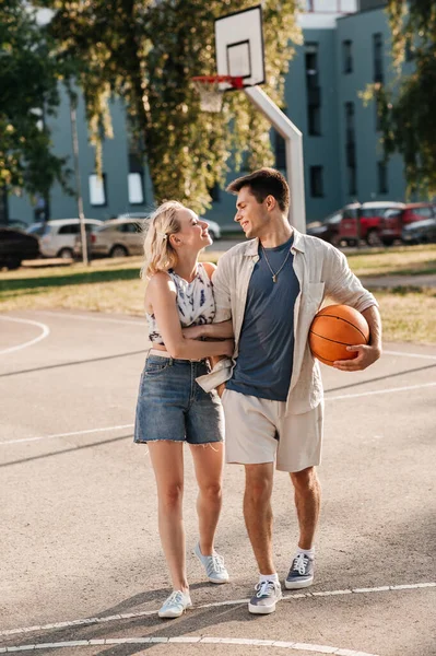 Feliz pareja con pelota en el patio de baloncesto — Foto de Stock