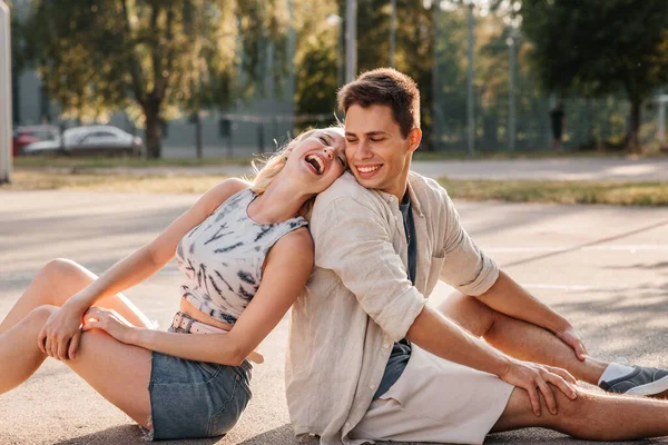 Feliz pareja sentada en el patio de baloncesto — Foto de Stock