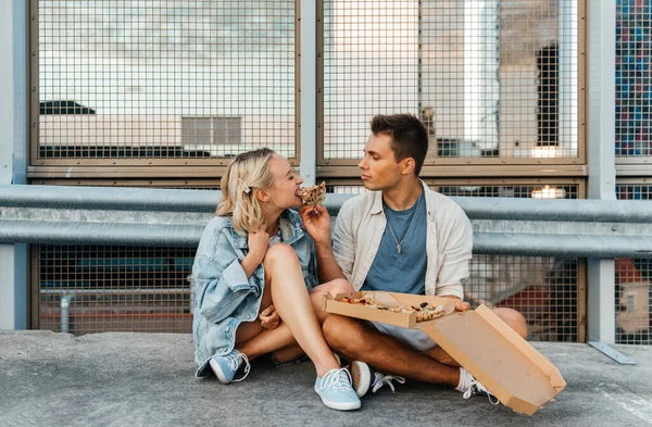 도시 옥상 주차장에서 피자를 먹고 있는 행복 한 부부 — 스톡 사진