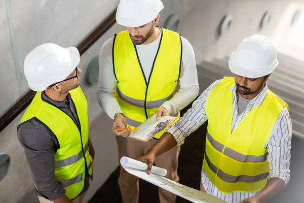 Architects in helmets with blueprint at office — Stock Photo, Image