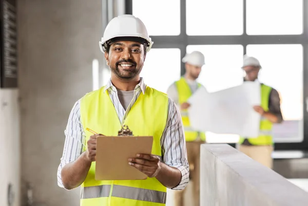 Arquiteto masculino no capacete com prancheta no escritório — Fotografia de Stock