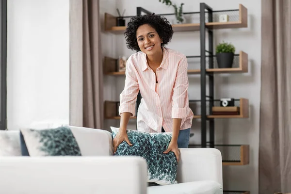 Femme heureuse arrangeant des coussins sur le canapé à la maison — Photo