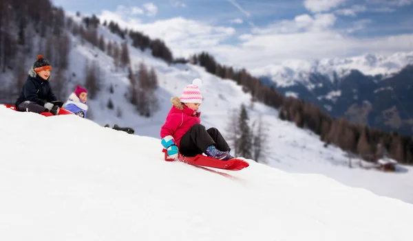 Enfants glissant sur des traîneaux descendant une colline de neige en hiver — Photo