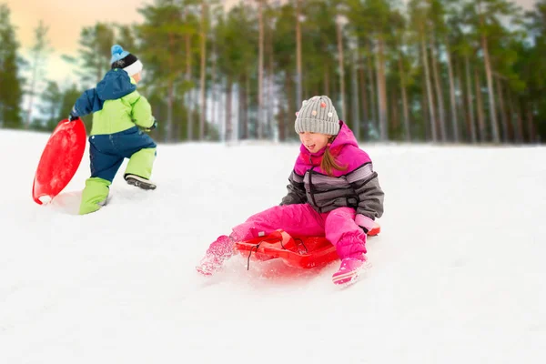Kinderen glijden op sleeën naar beneden heuvel in de winter — Stockfoto