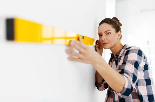 Щаслива жінка з рівнем вимірювальної стіни вдома — стокове фото