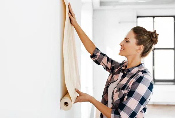 Mujer aplicando fondo de pantalla a la pared en casa —  Fotos de Stock