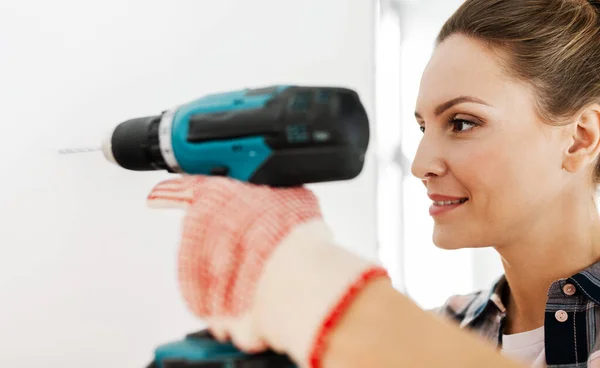 Woman with perforator drilling wall at home — Stock Photo, Image