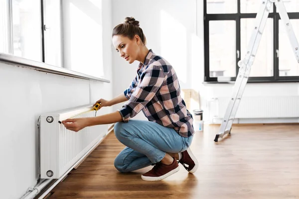 Woman with ruler measuring heater at home — Stock Photo, Image