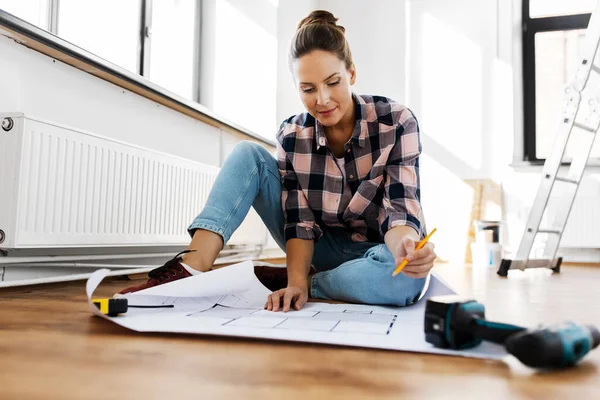 Woman with blueprint sitting on floor at home — Stock Photo, Image