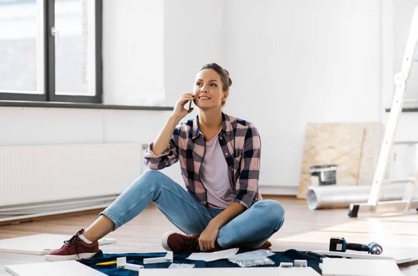 Woman assembling furniture and calling on phone — Stock Photo, Image