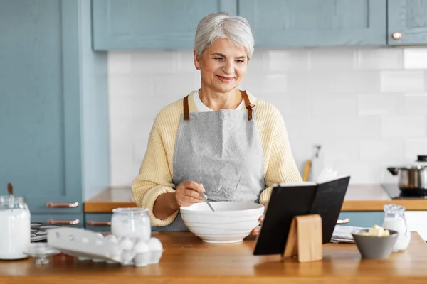 Счастливая женщина с кулинарной книгой для приготовления пищи на кухне — стоковое фото