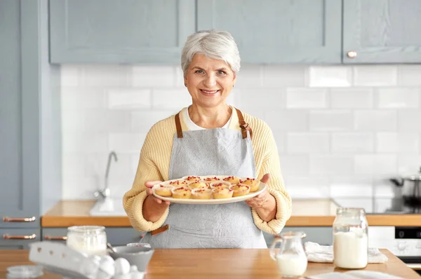 Mulher segurando prato com cupcakes na cozinha — Fotografia de Stock