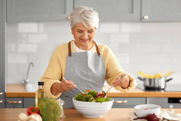 Щаслива жінка готує салат на кухні вдома — стокове фото