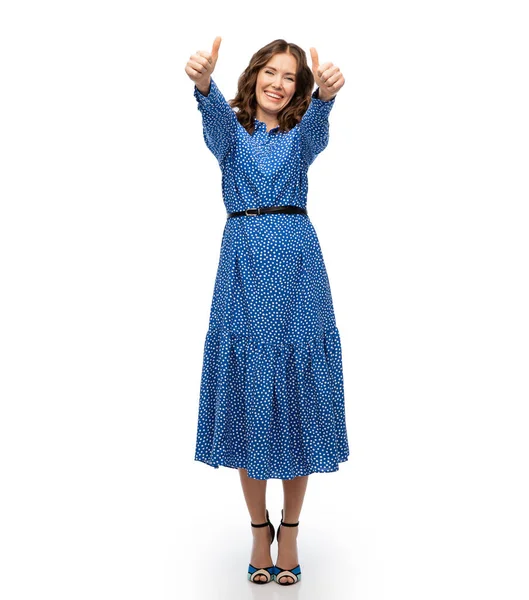 Boldog fiatal nő kék ruhában mutatja hüvelykujját felfelé — Stock Fotó