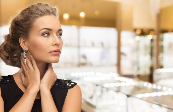 Femme avec boucles d'oreilles en diamant à la bijouterie — Photo