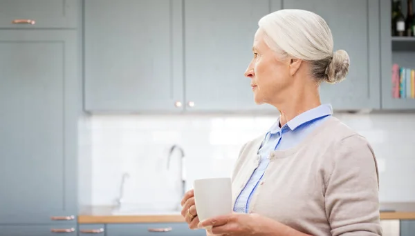 Одинокая женщина с чашкой чая или кофе на кухне — стоковое фото