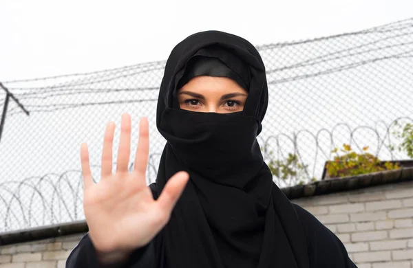 Γυναίκα με μαντίλα δείχνει σήμα στοπ πάνω από αγκαθωτό σύρμα — Φωτογραφία Αρχείου