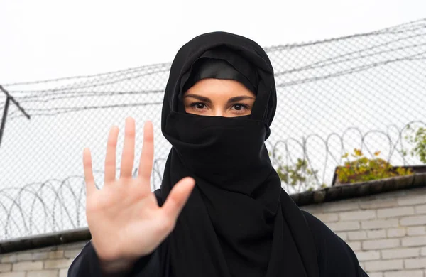 Woman in hijab showing stop sign over barbed wire — Stock Photo, Image