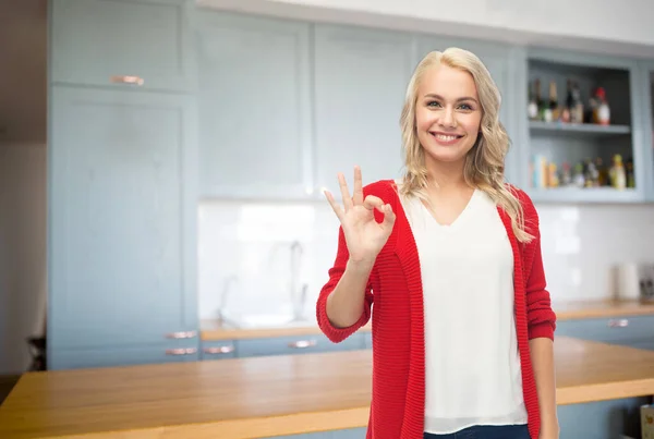 Šťastná mladá žena ukazuje ok ruční znak na kuchyni — Stock fotografie
