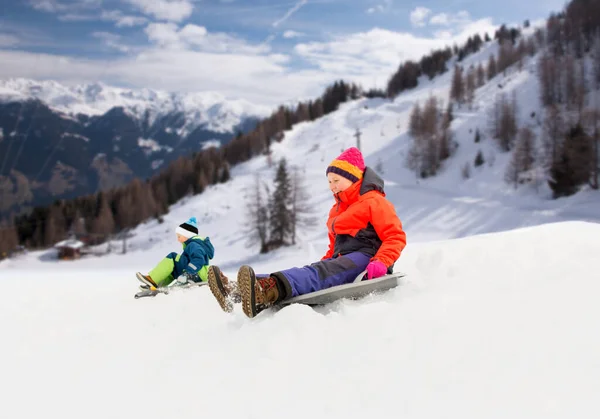 Enfants heureux glissant sur des traîneaux descendant la colline en hiver — Photo