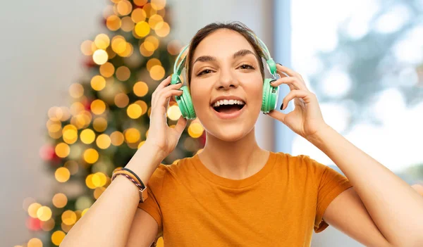Lykkelig ung kvinde med hovedtelefoner på jul - Stock-foto