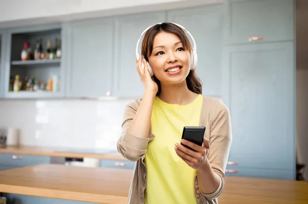 Vrouw in hoofdtelefoon luisteren naar muziek op keuken — Stockfoto